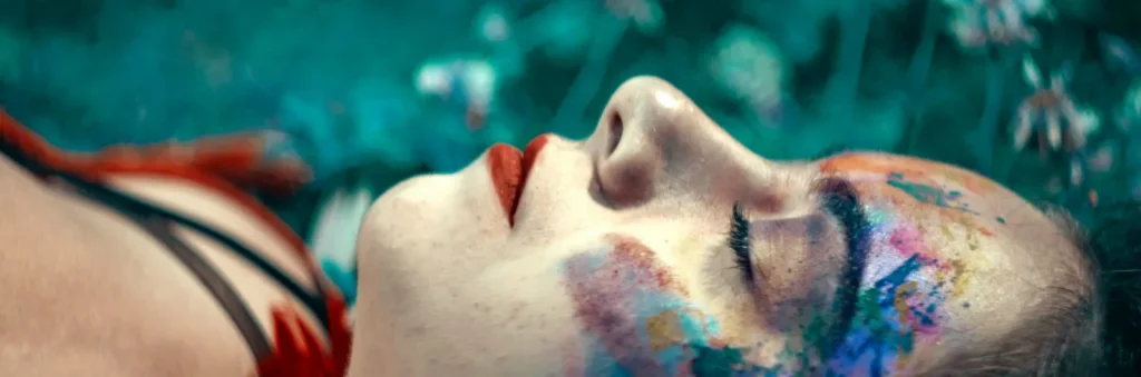 Woman laying in grass with colored paint on her face