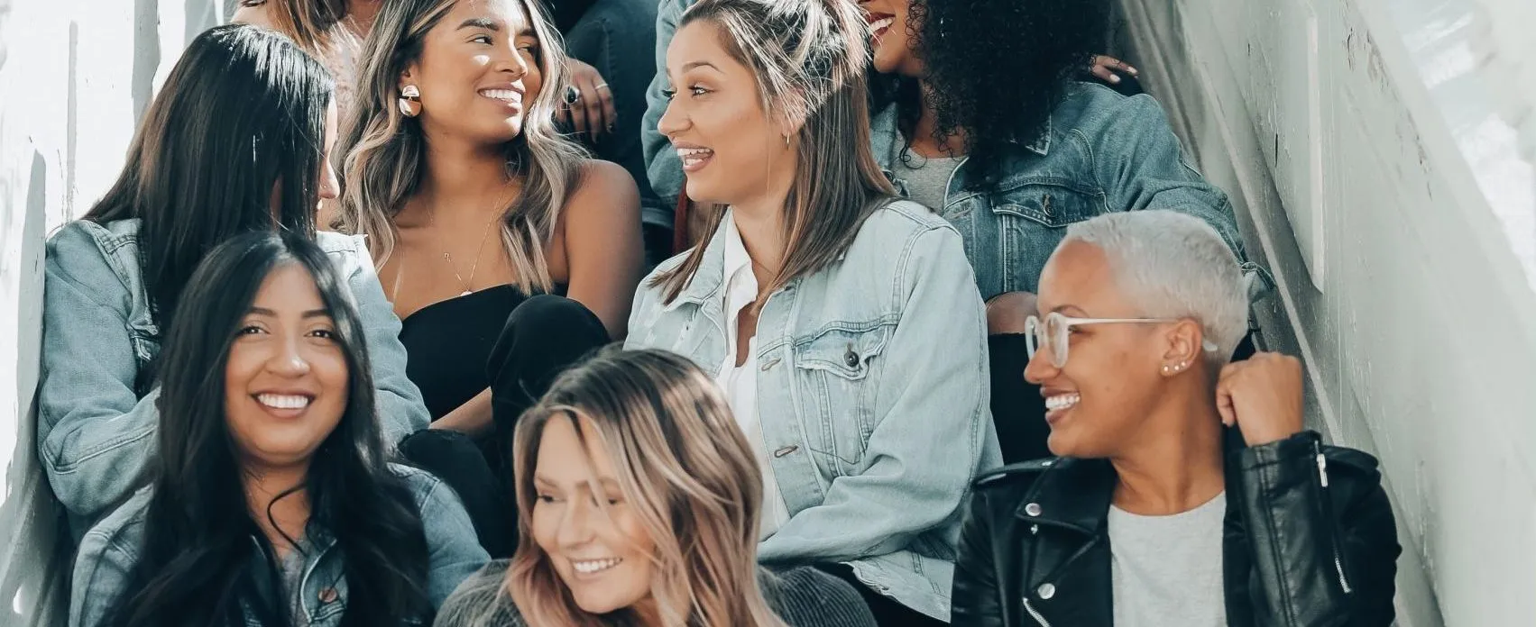 Women in denim laughing together on outdoor stairs, from The Un-dependents get involved feature