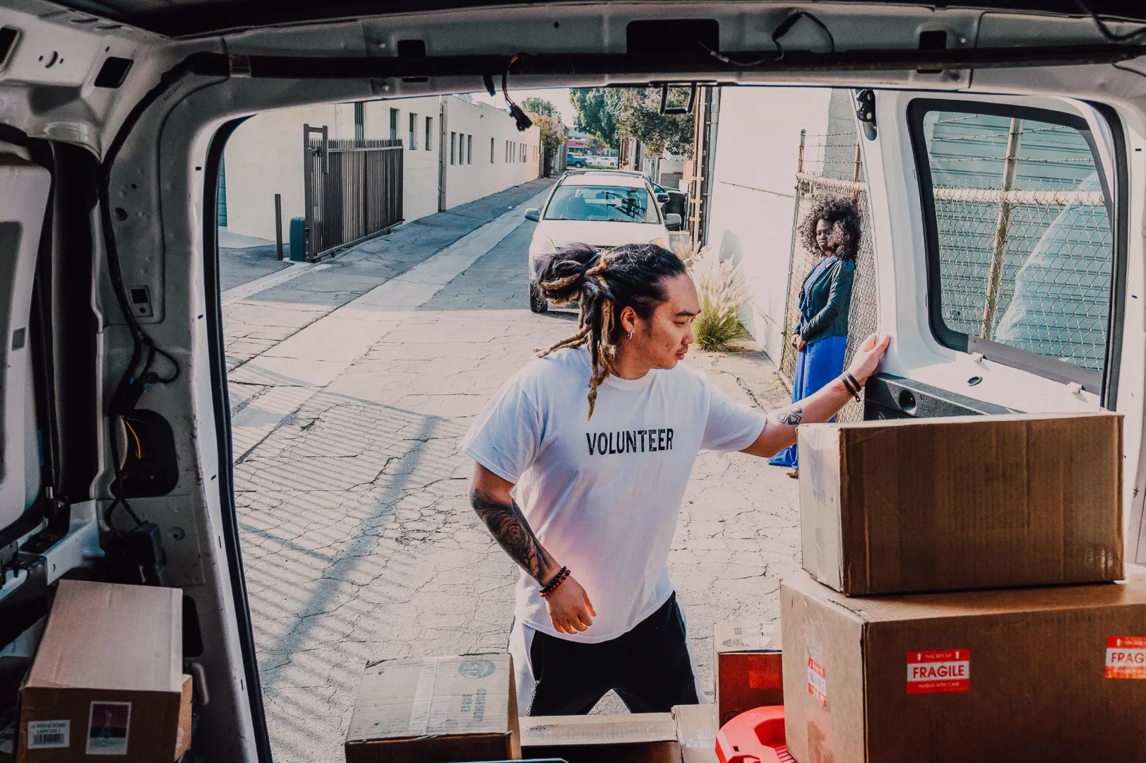 Man in a volunteer t-shirt loading cardboard boxes into the back of a van