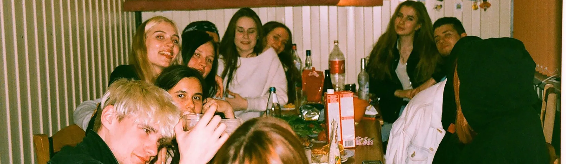 Friends drinking and laughing around a cluttered party table, from The Un-dependents in numbers feature