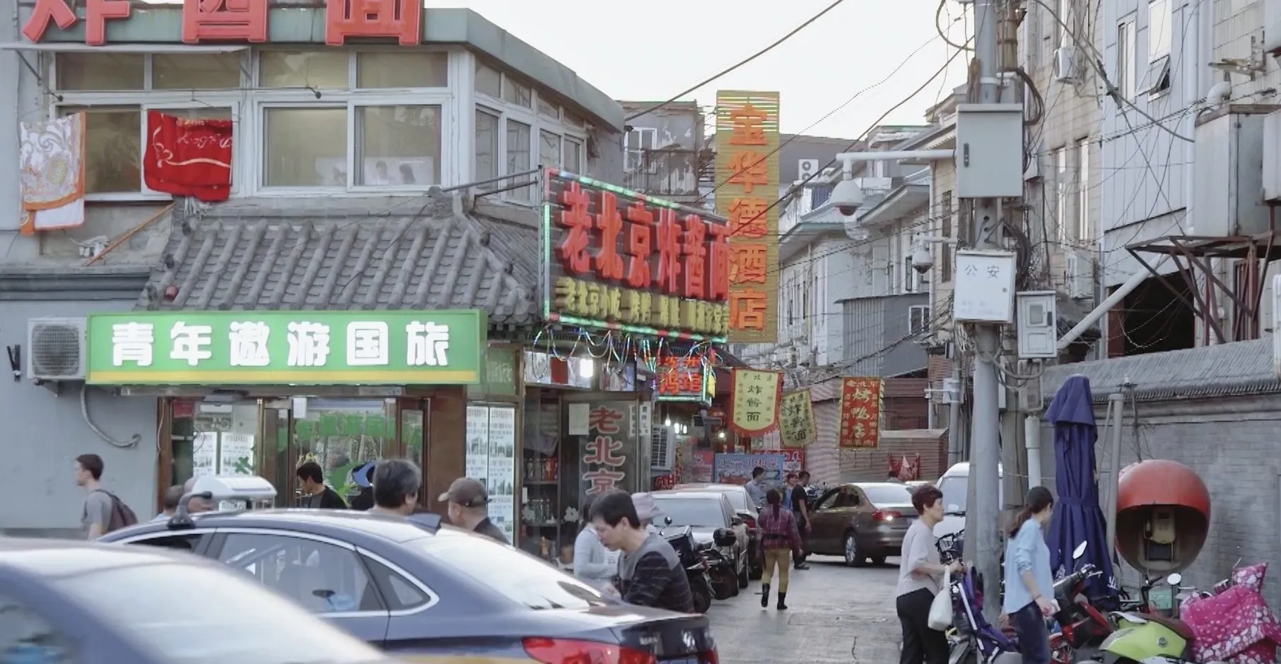 Busy Beijing side street with neon signs, traffic and hazy air, setting for air pollution research